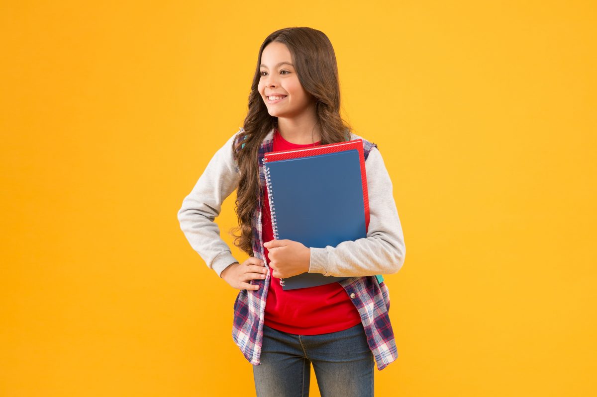 Young teen smiling and holding notebooks