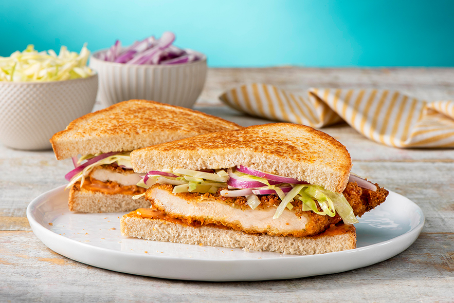 Chicken cutlet sandwich with a bowl of cabbage slaw in the background